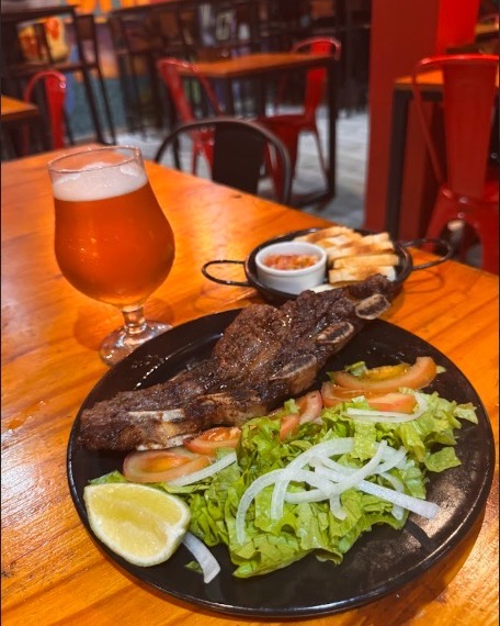 Corte de carne a la parrilla con ensalada y una copa de cerveza artesanal
